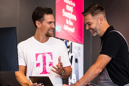 Zwei Männer beraten sich im Telekom Shop am Tablet, Kundenservice vor Ort